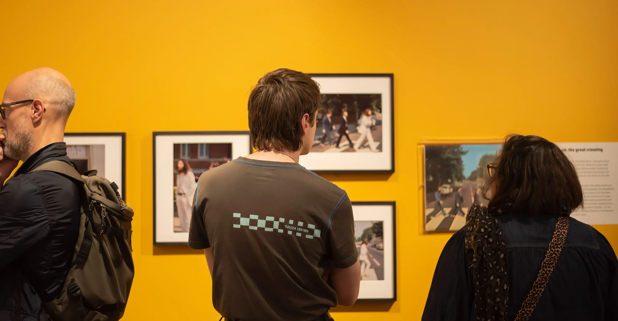 Three people in a Gallery looking at framed images in an exhibition