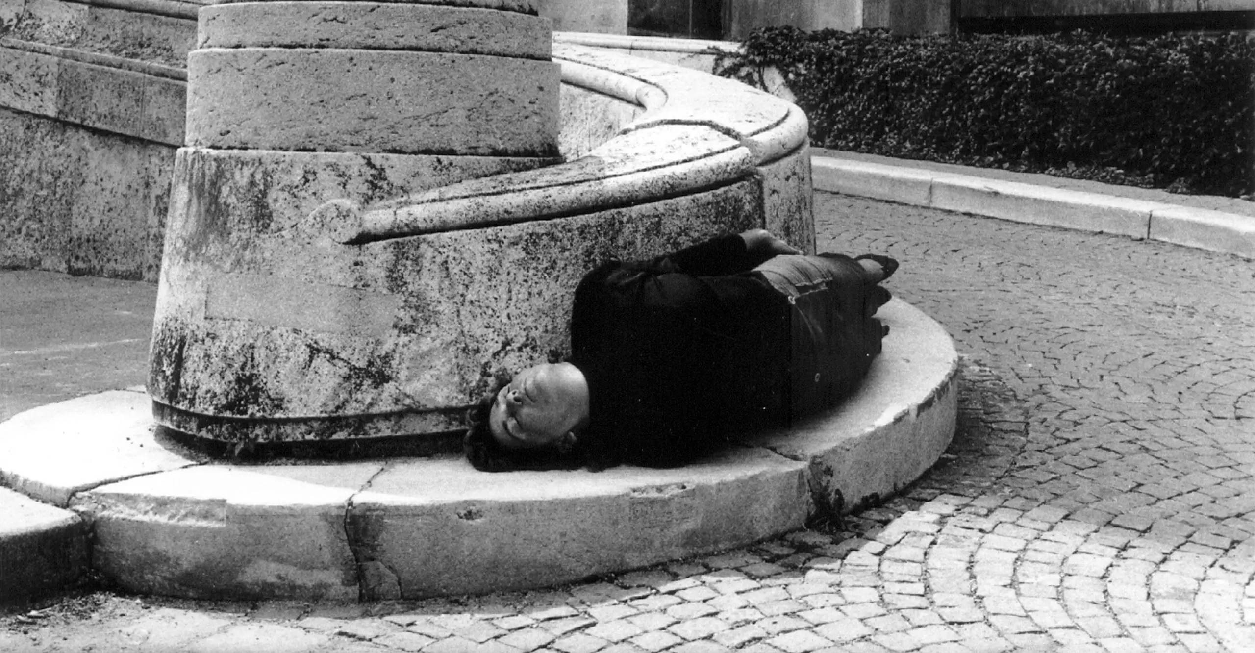 Black and white photo of a person lying around a pavement