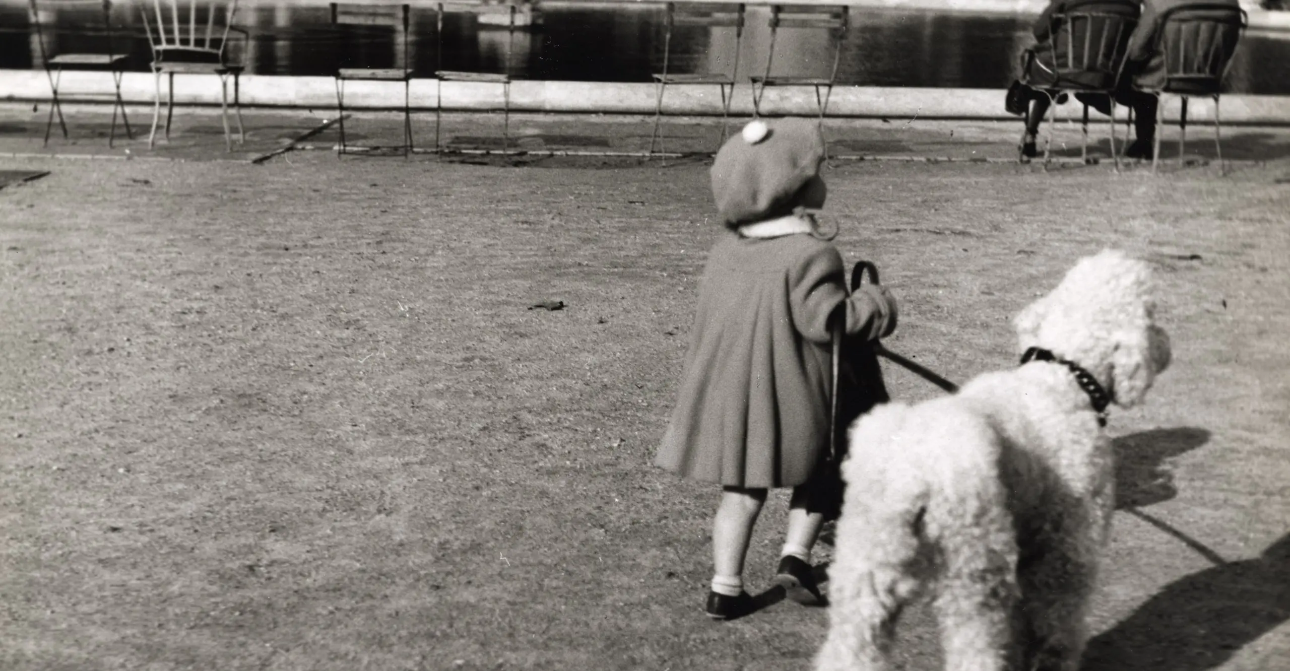 Black and white photograph of a young person holding a dog on a lead in a Paris park