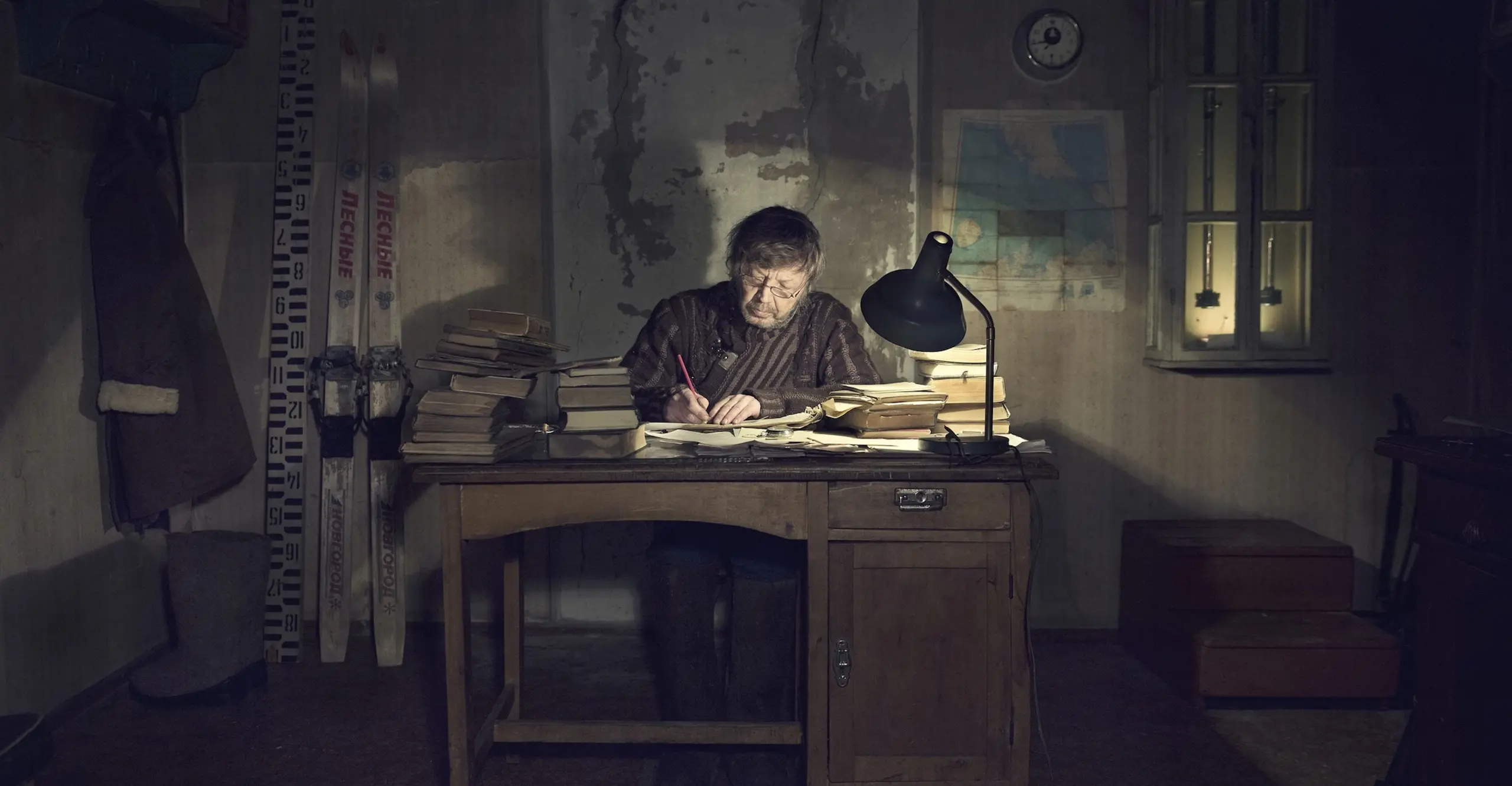 A man sits at a desk in a dark room.