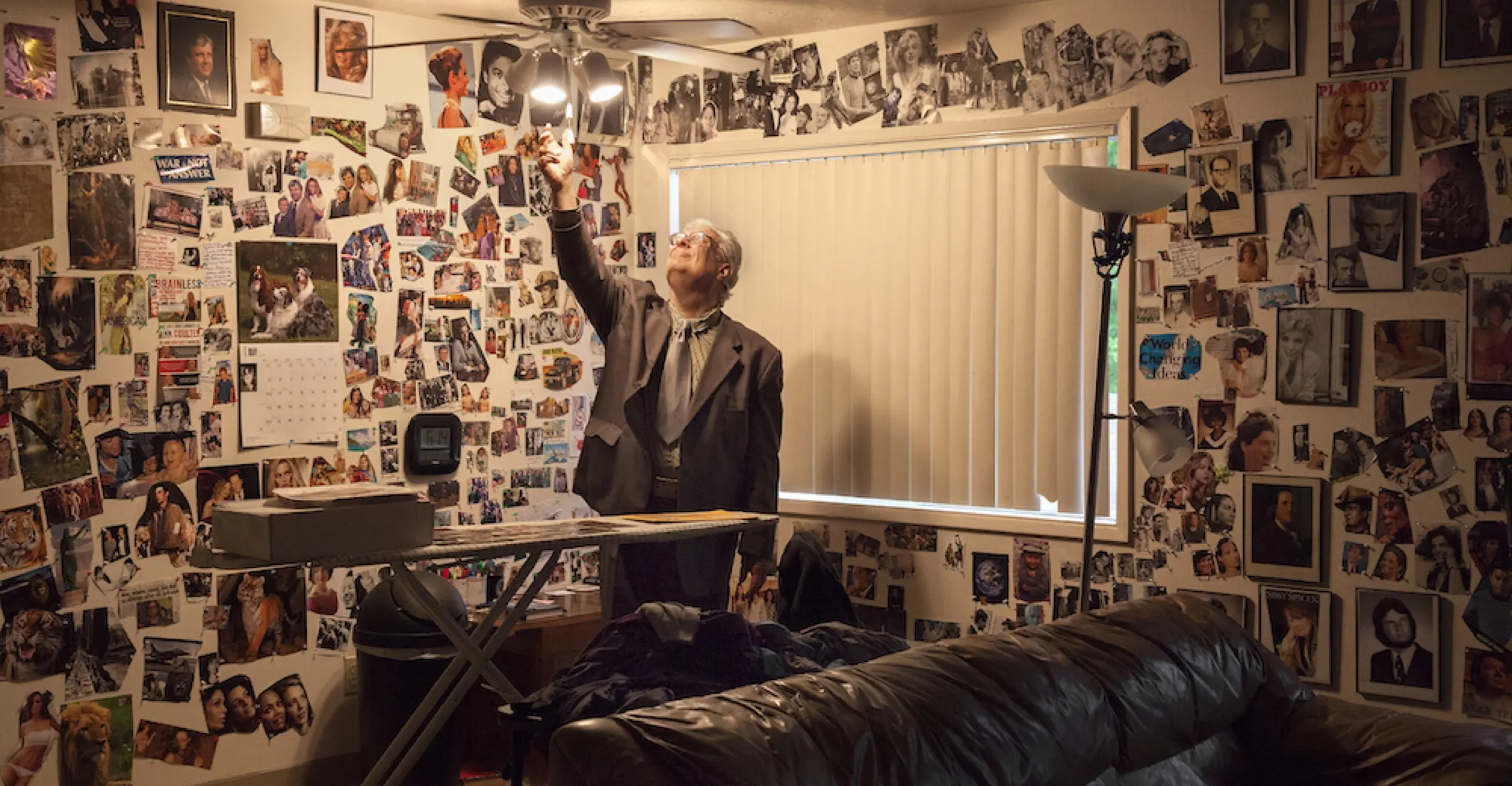Man in centre of room covered in photographs 
