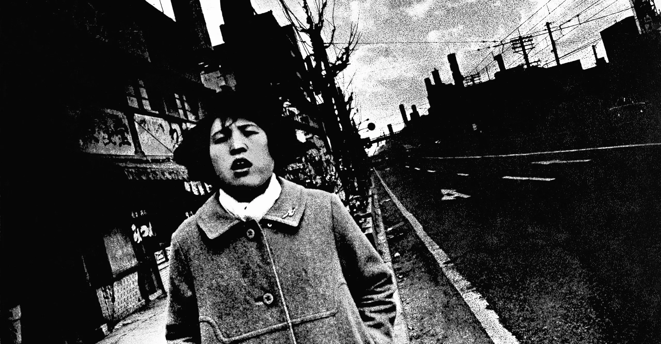 High contrast black and white photograph of a tilted street scene with an open mouthed young person