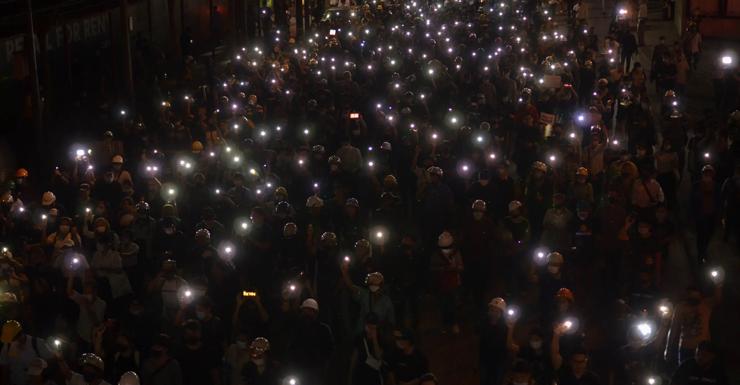 A photograph of a crowd of people holding lights in the night.