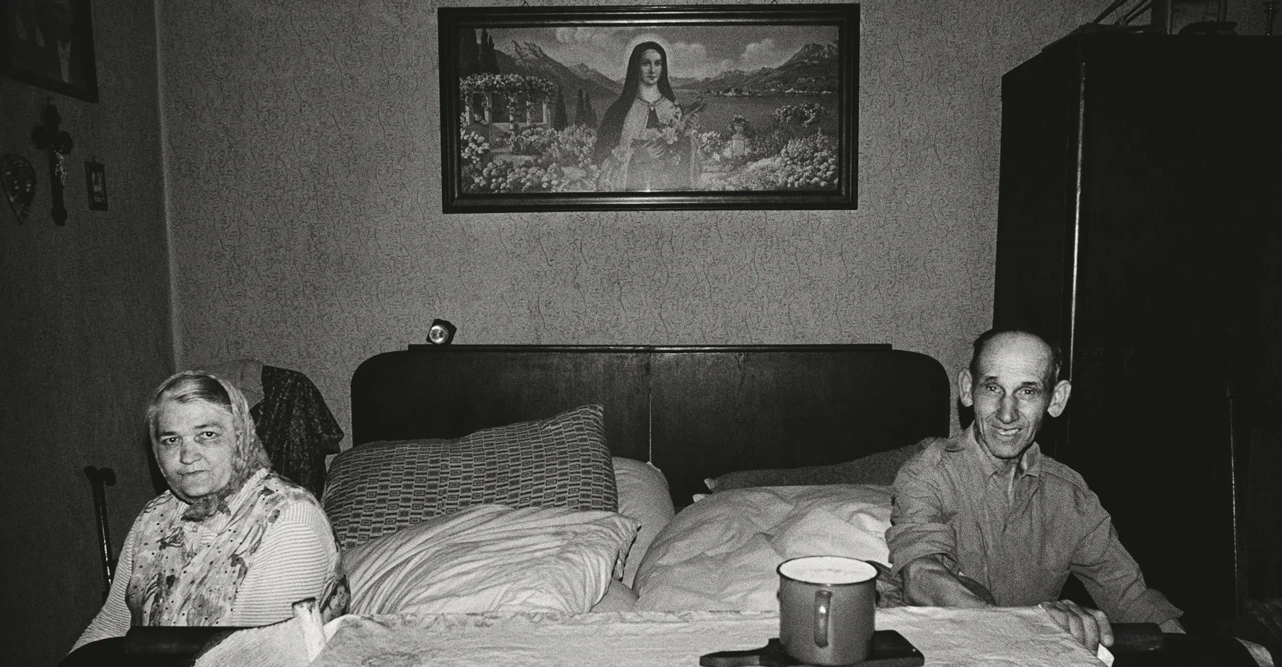 Two people sitting on either side of a bed