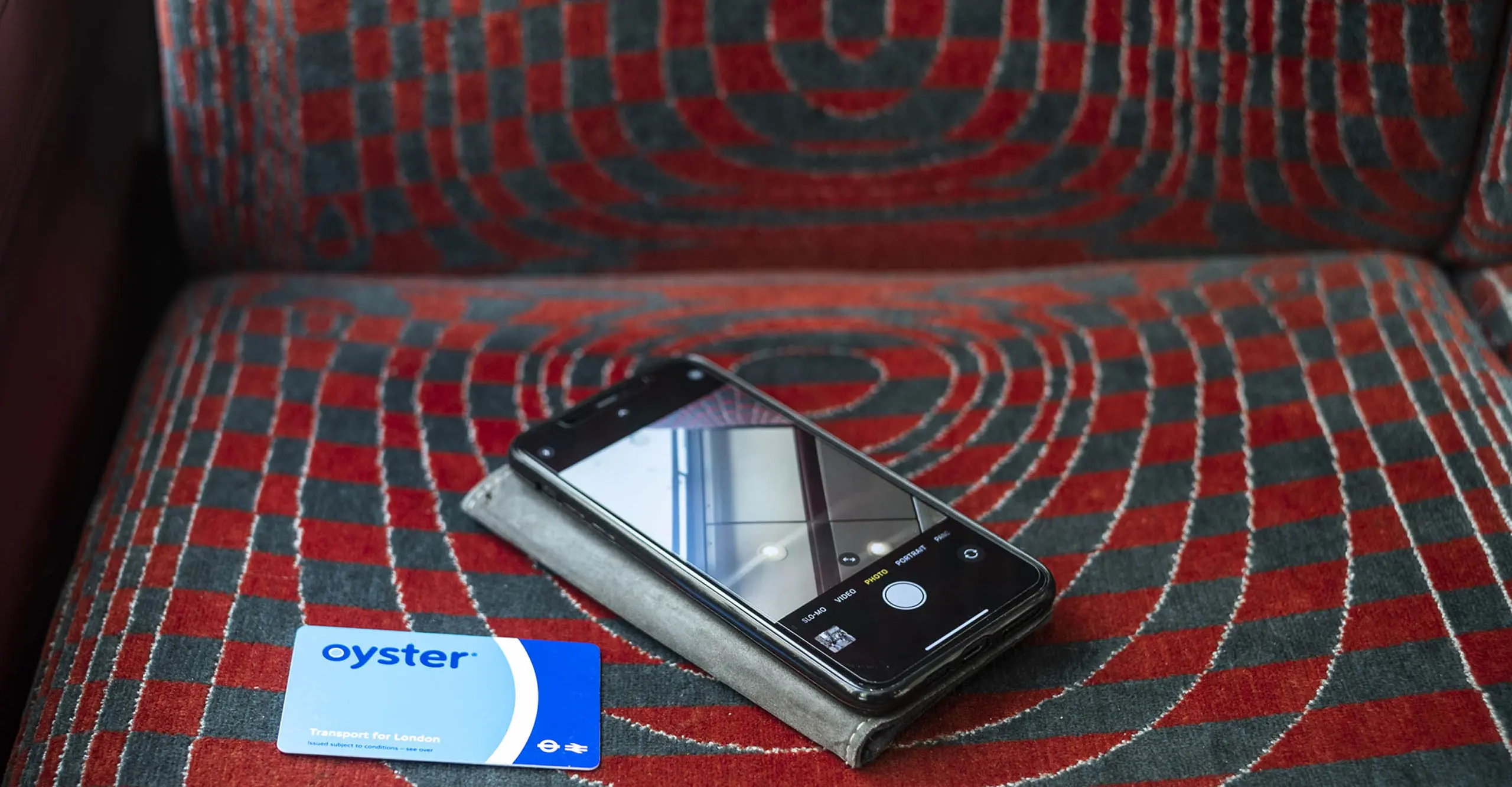 A photograph of a mobile phone and a travel card placed on a bus seat.