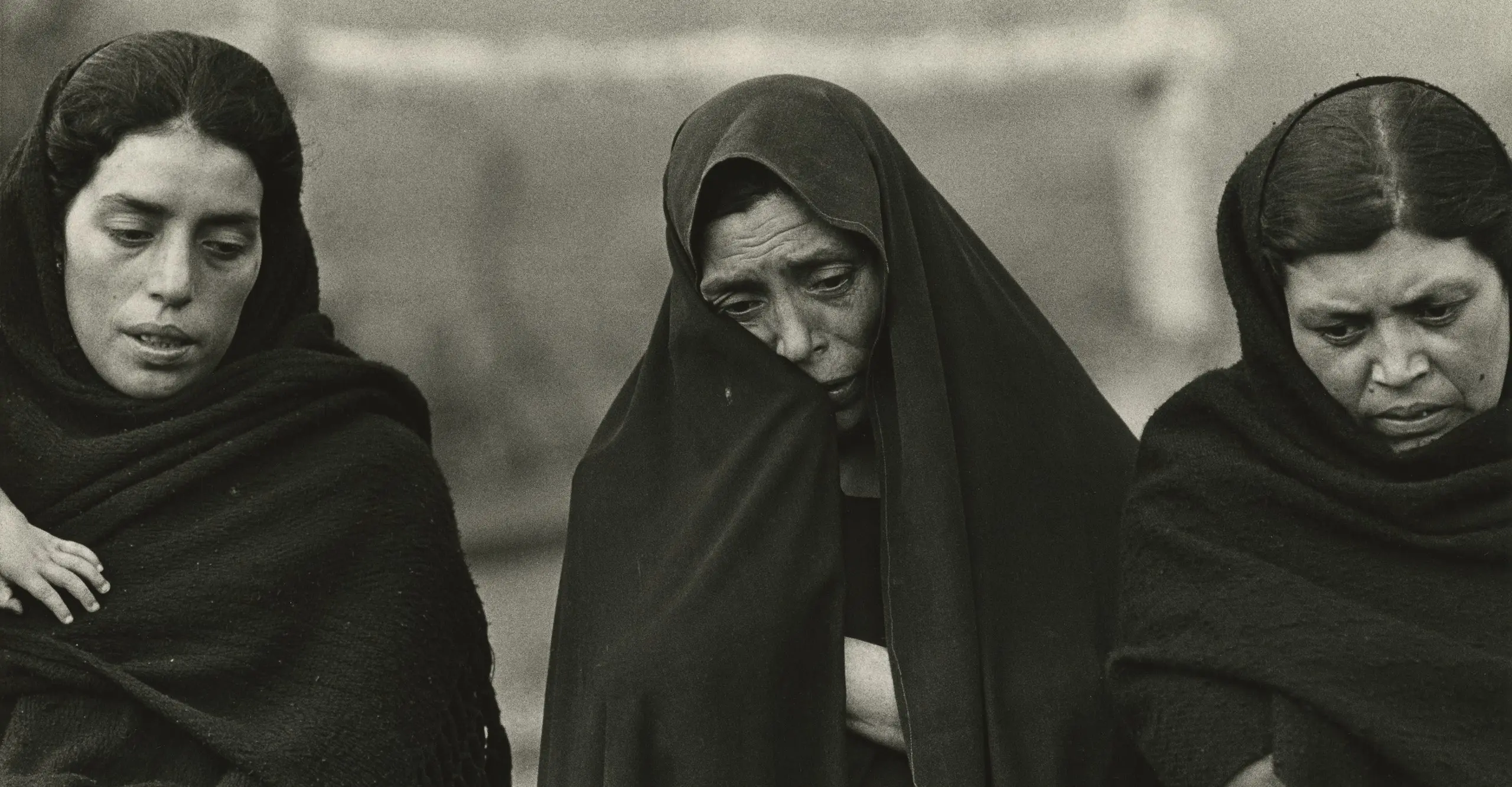 Black and white photograph of three women with black headscarves wrapped around them