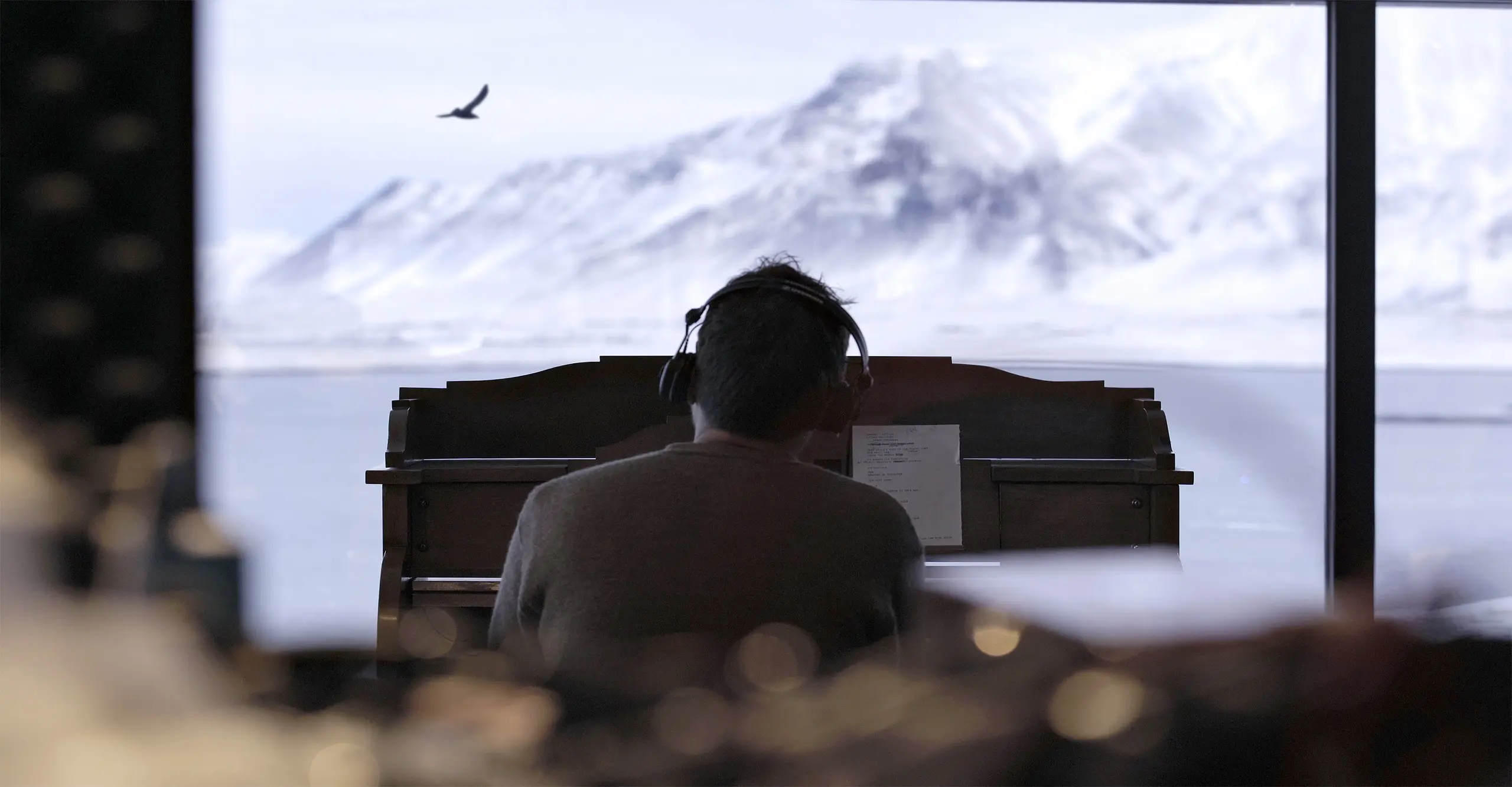 Damon Albarn at piano looking out over snowy mountain