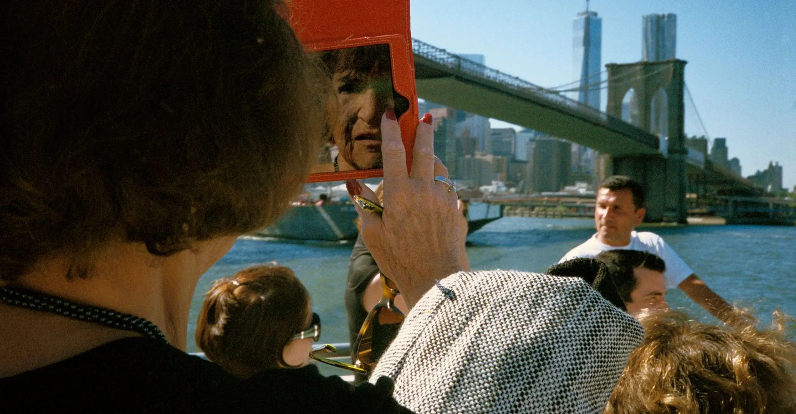 Colour photo of women looking into mirror by Brooklyn Bridge