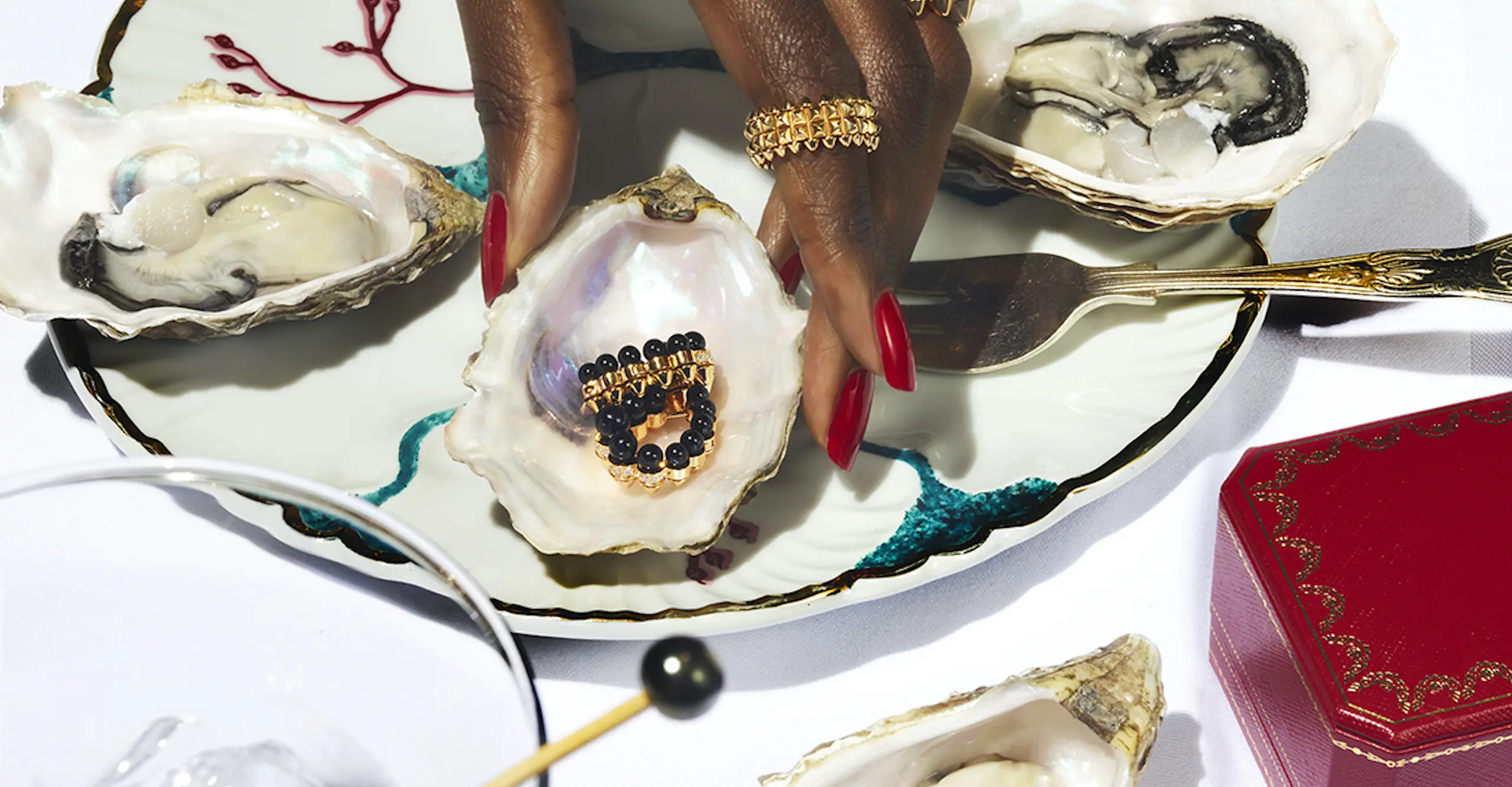 Photo of a woman picking up a shell with earrings in it. 