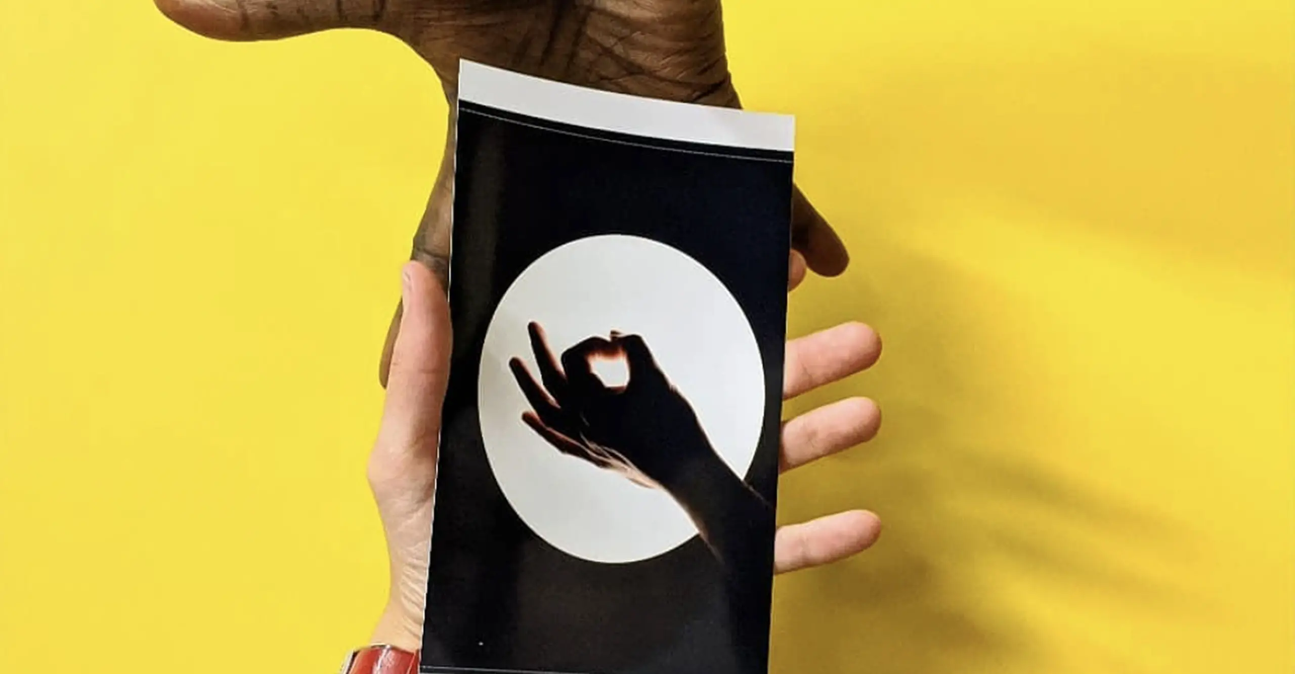 A photograph of 2 hands holding a printed photograph with a yellow background behind