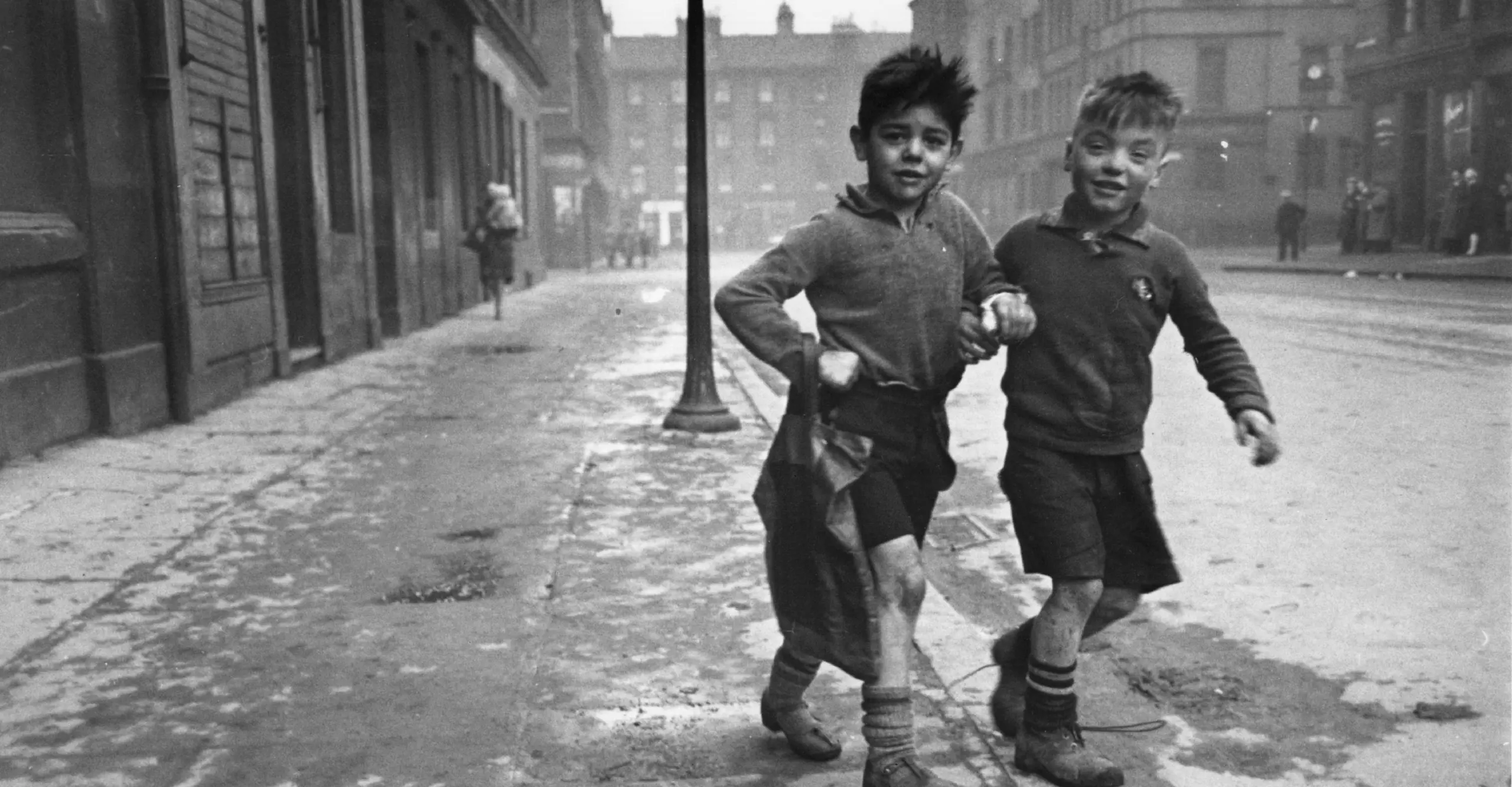 Black and white photo of two boys walking through the streets of Glasgow.