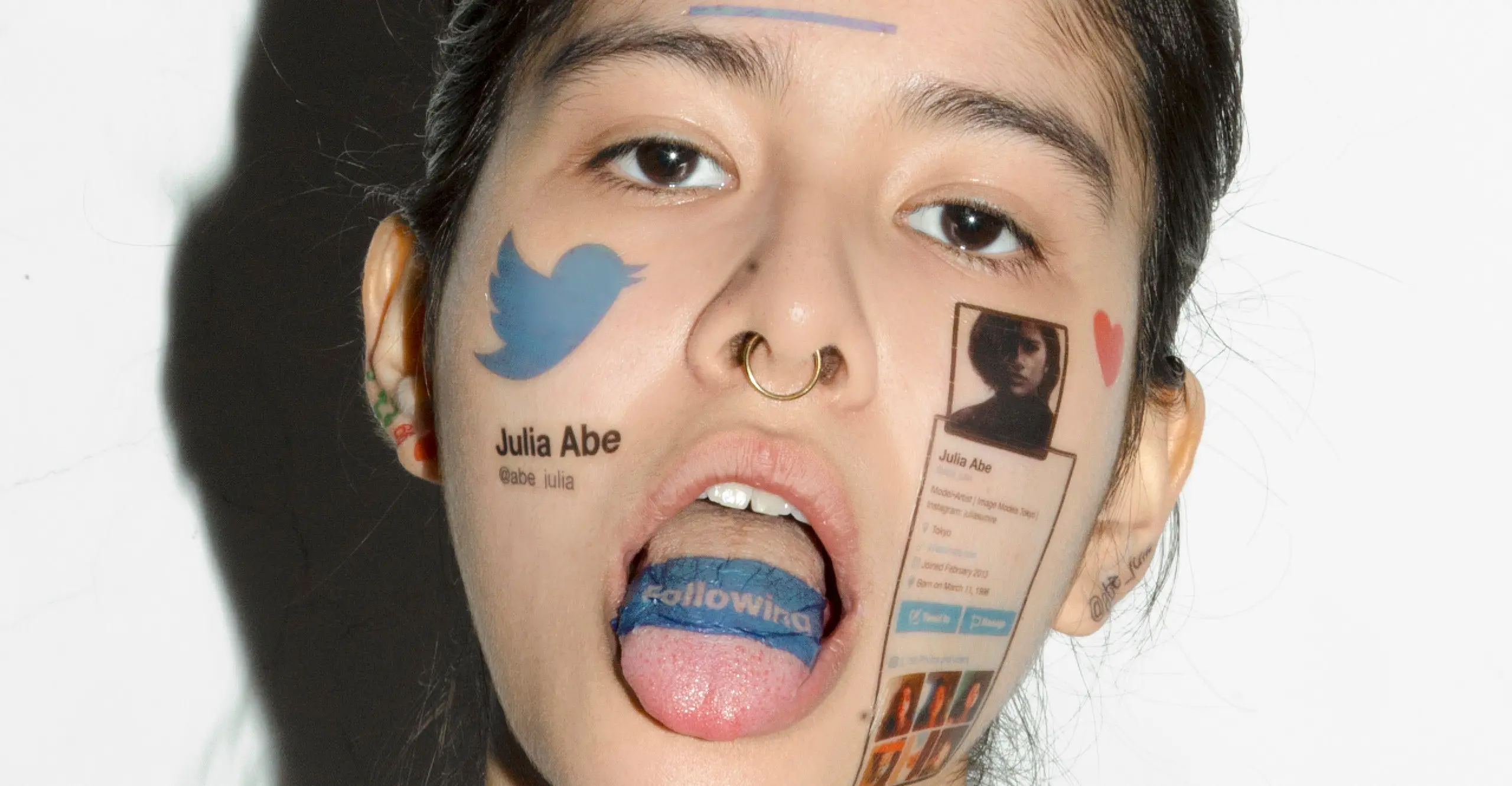 Photograph of a person's face with their tongue stuck out and Twitter logos tattooed onto their tongue, cheeks and forehead.