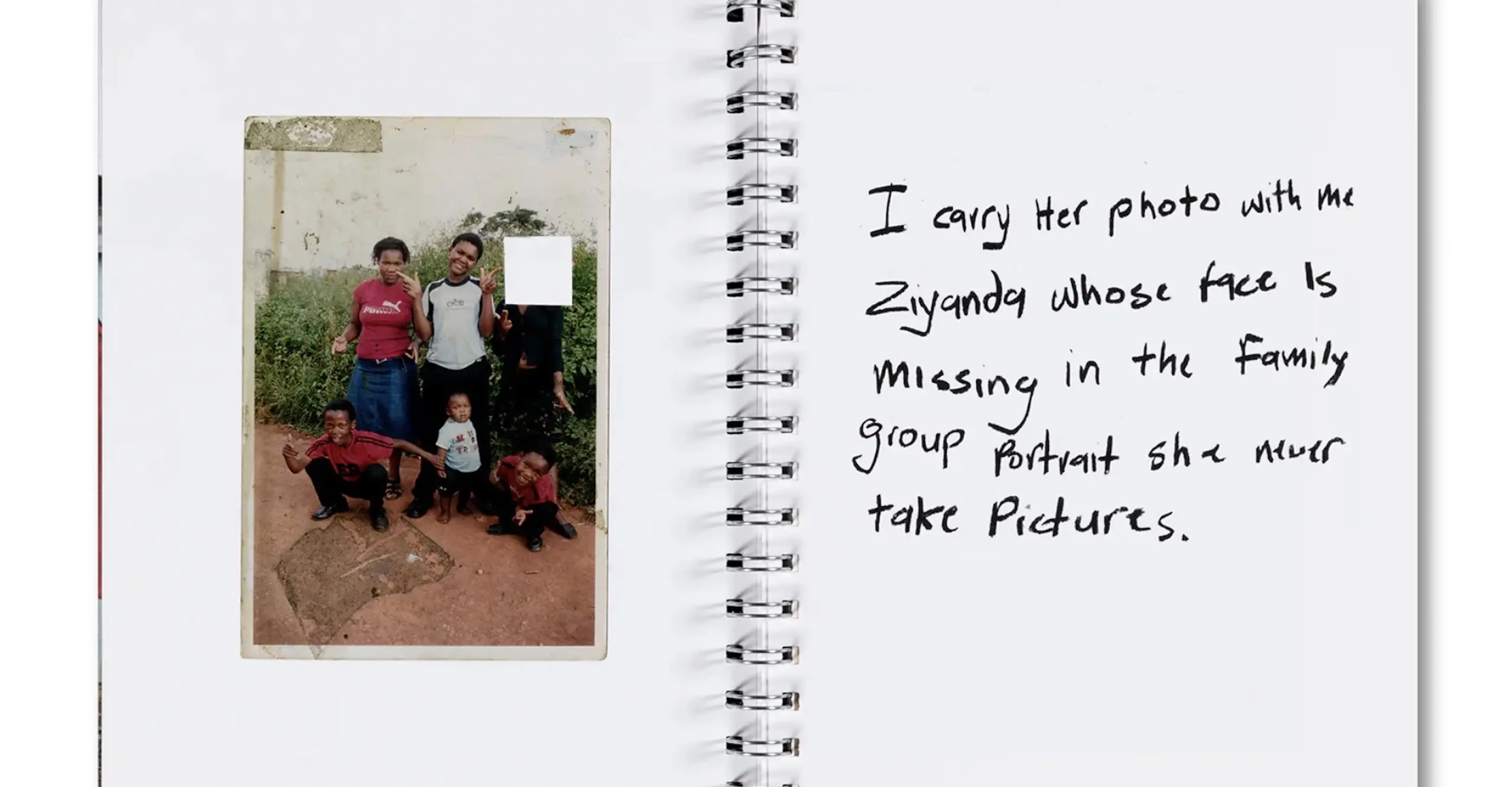 Colour photograph of a book spread with a photograph on a family on one side and handwriting on the other