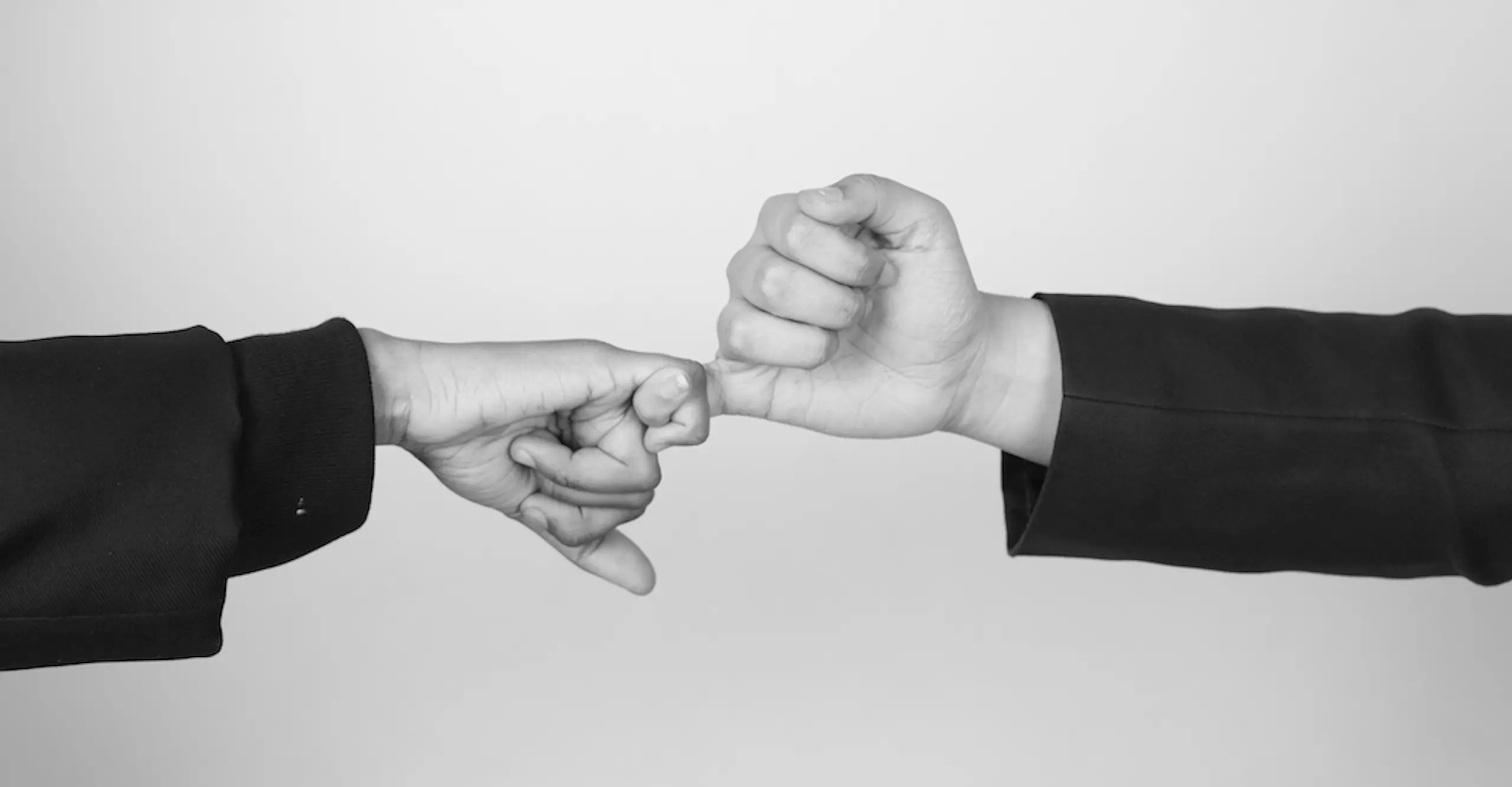 Black and white photograph of hands interlocking with little finger.