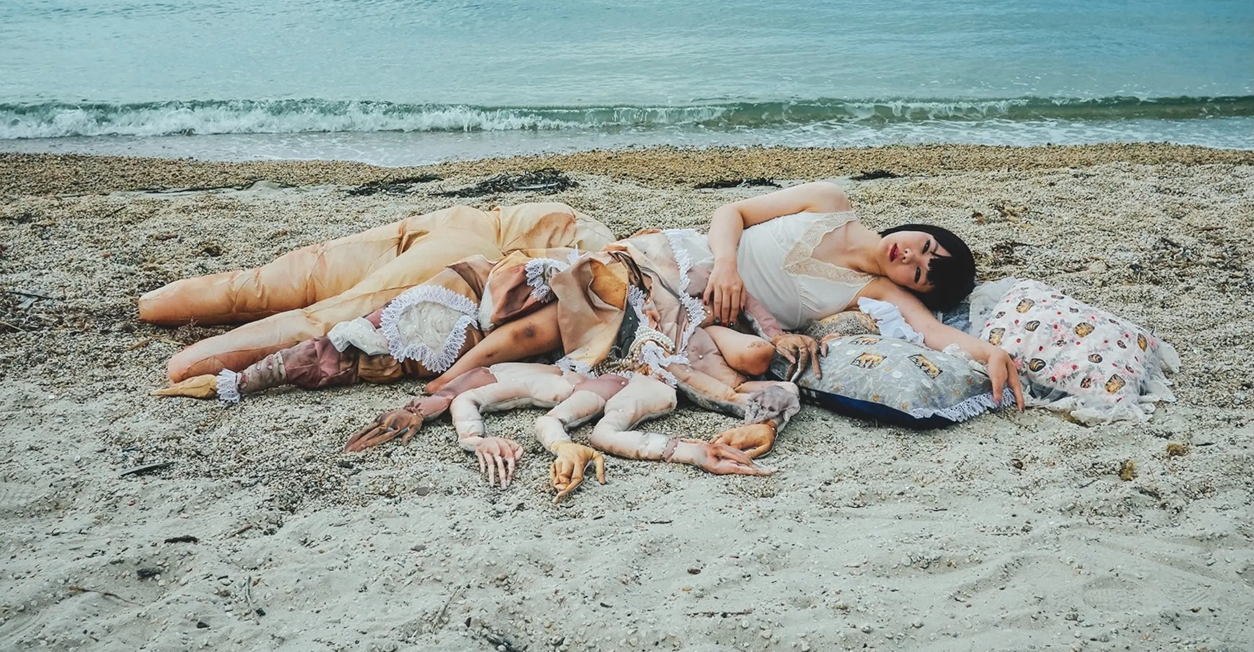 Figure lying on the beach next to arms fabricated from material