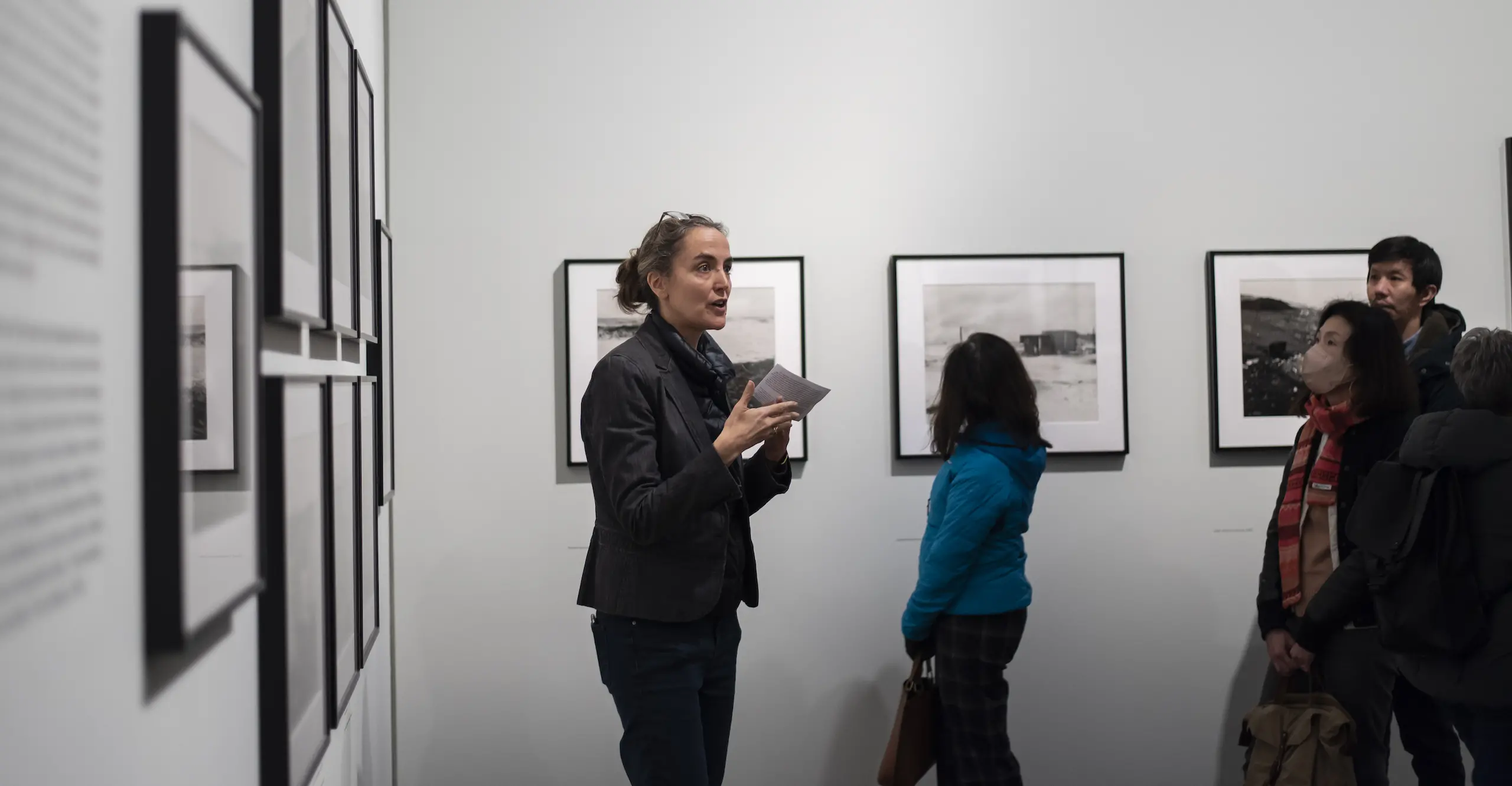 A person talking to a group of people in a photography exhibition.