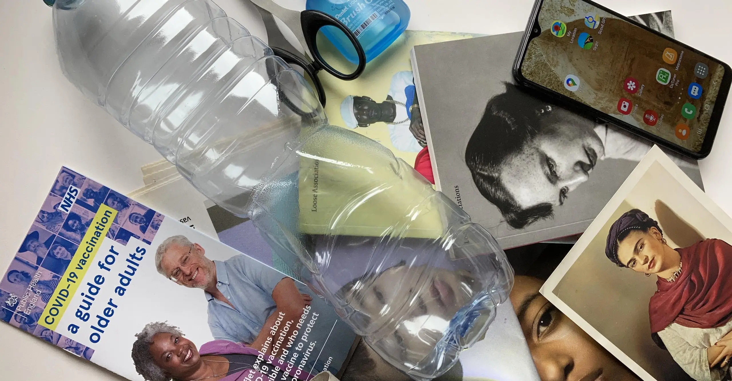 A photograph of a range of materials on a table including a plastic bottle, glue and scissors.