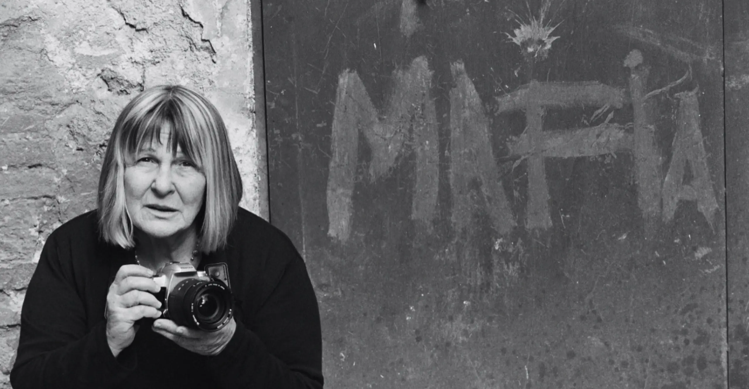 Black and white photo of Letizia Battaglia holdiing her camera 