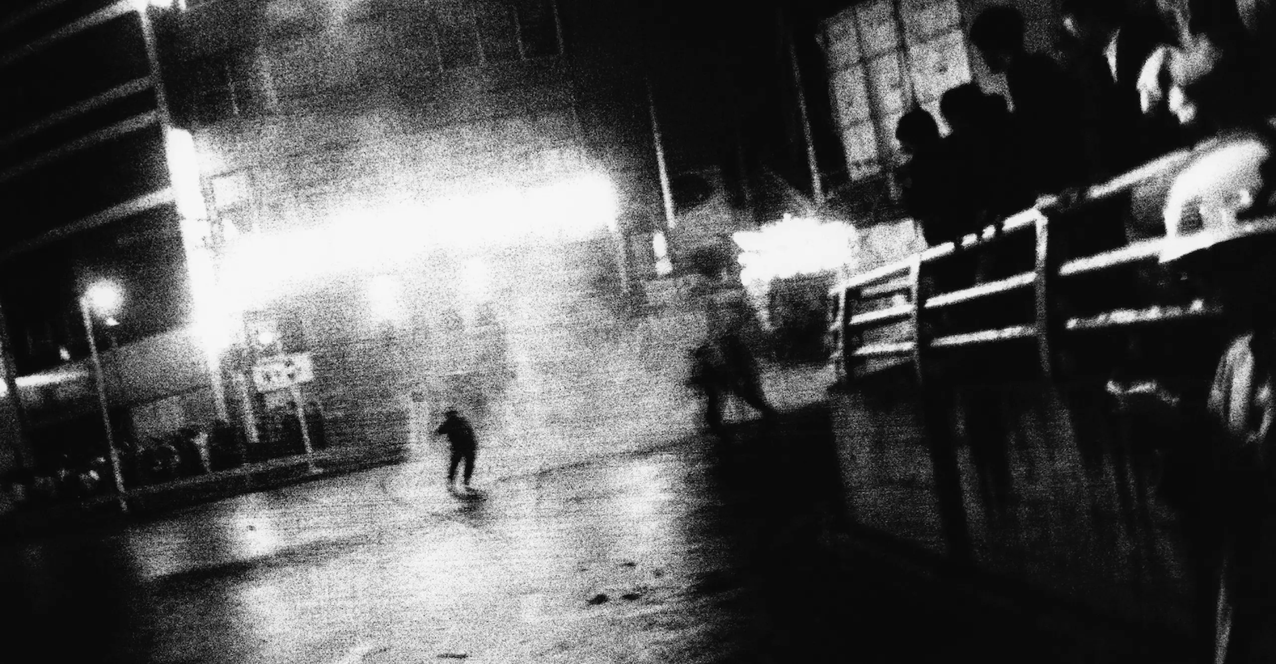 Blurred black and white image of a crowded street scene with one figure in the middle