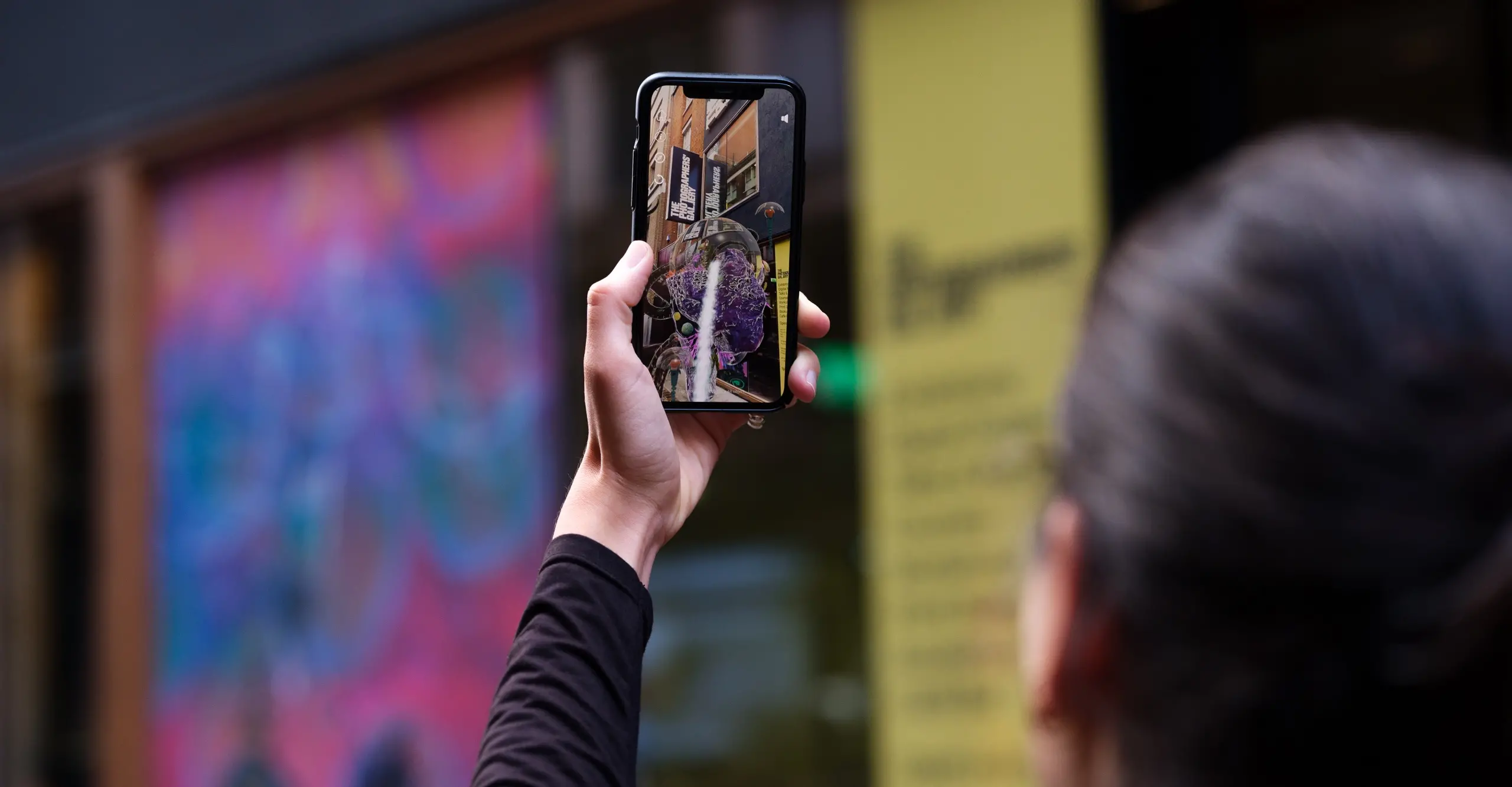 A Photograph of a gallery visitor using a mobile device to view an augmented reality artwork.