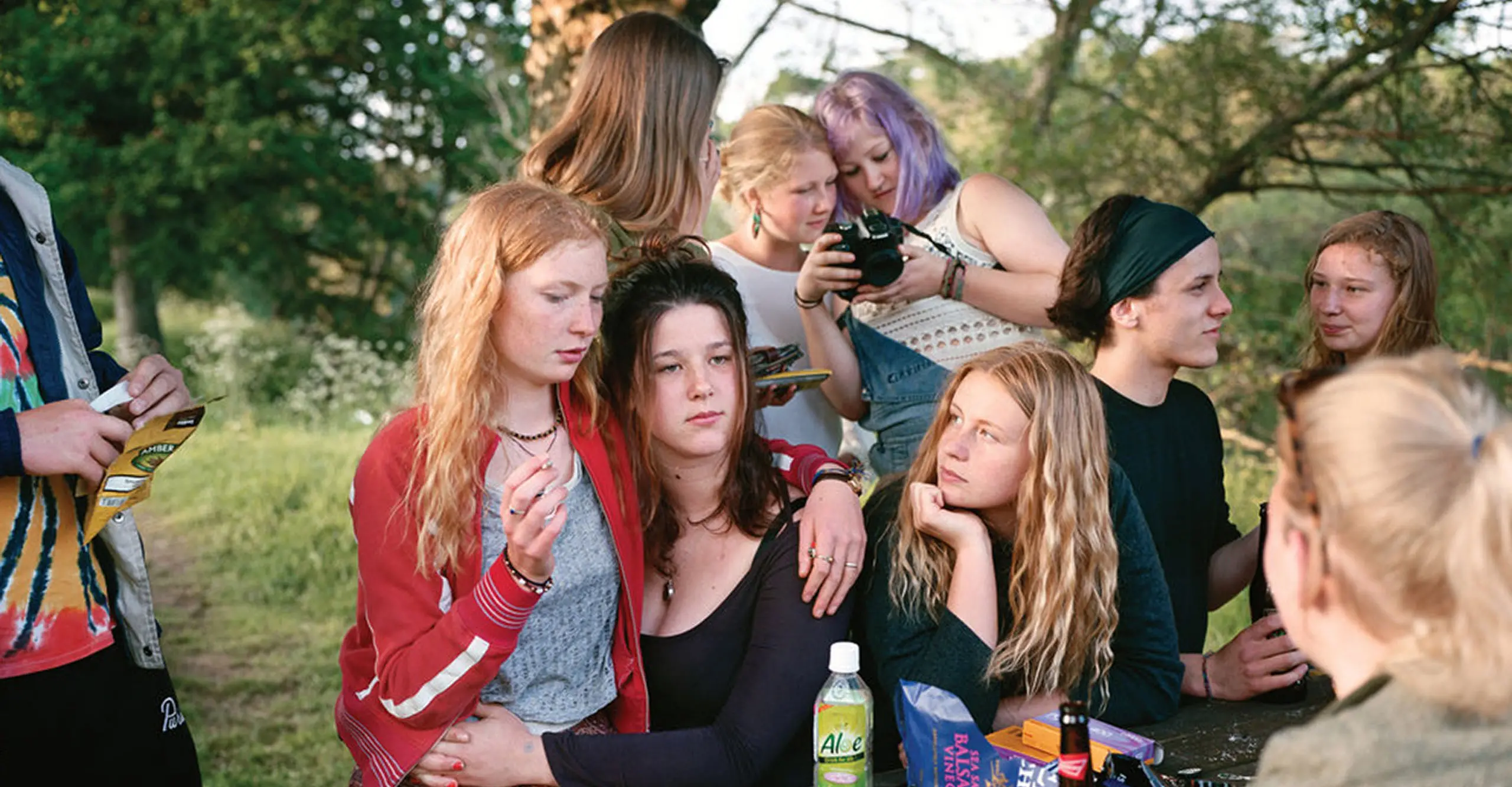 A photograph of a group of teenagers outside under a tree.