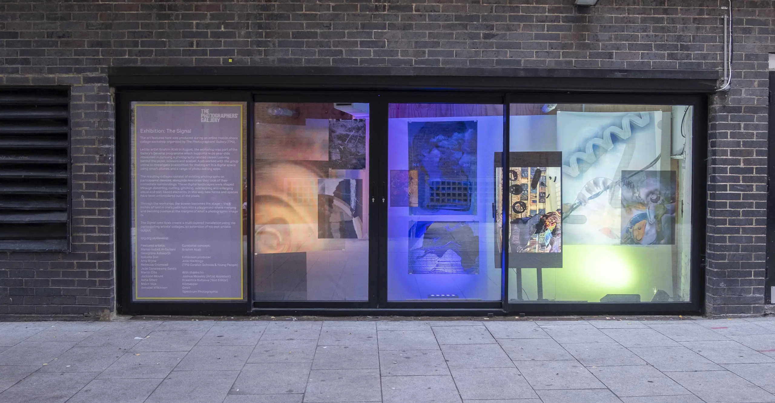 A photograph of a window front lit up with digital images.