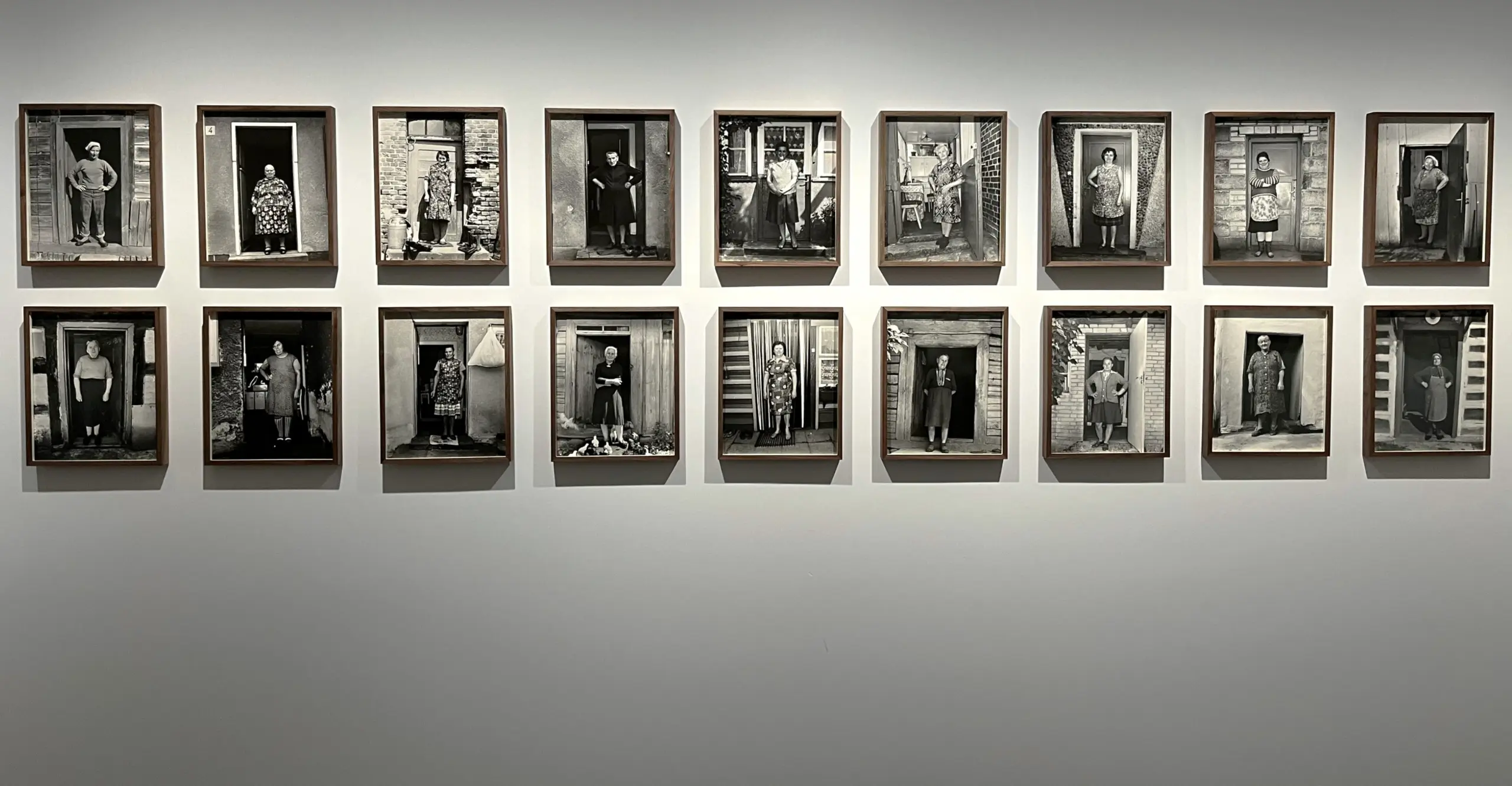 A series of framed photographs depicting various solo women stood in doorways. 