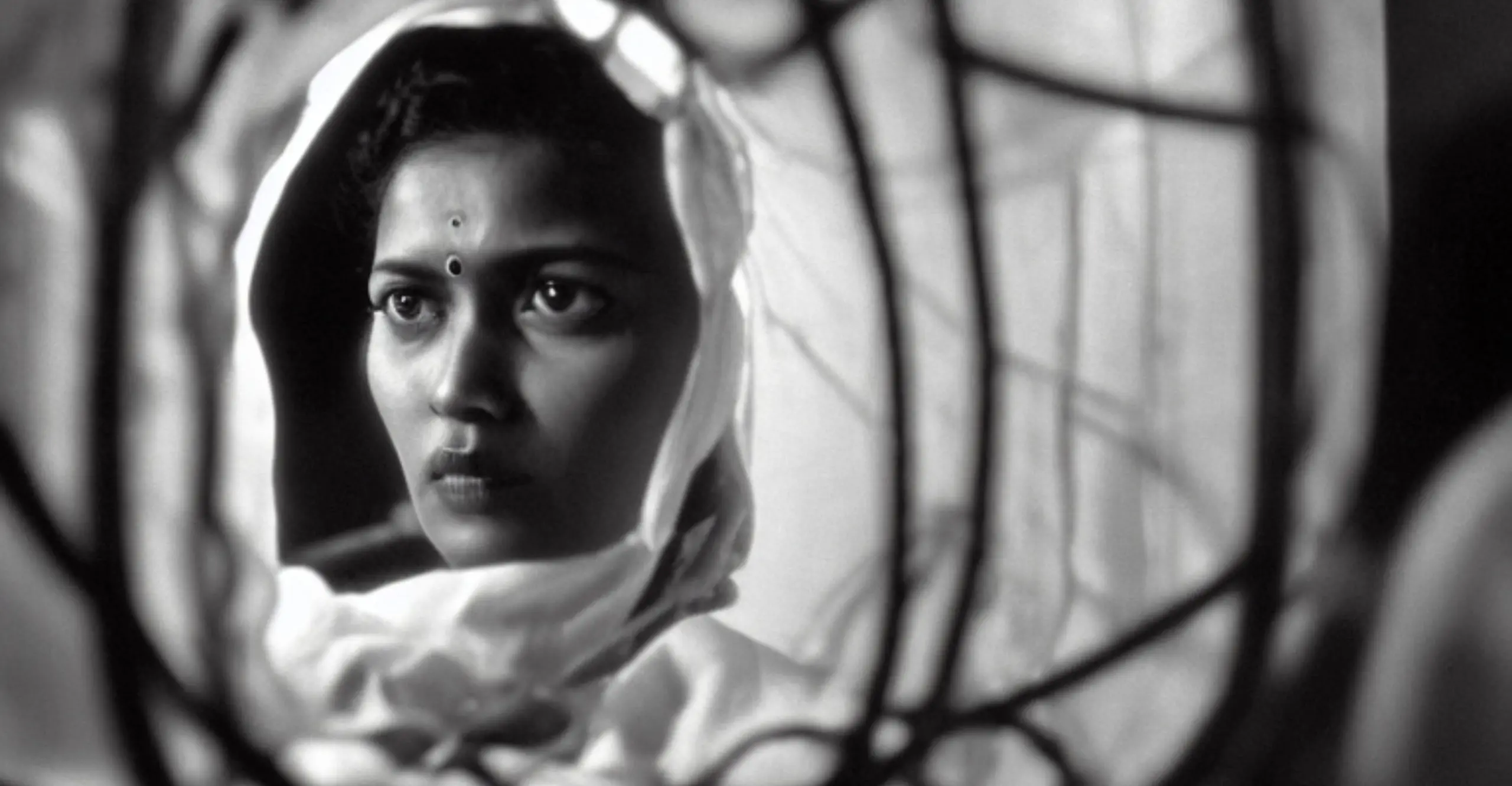 A black and white image of a woman with two bindis, a dot in the forehead, and a blurred background