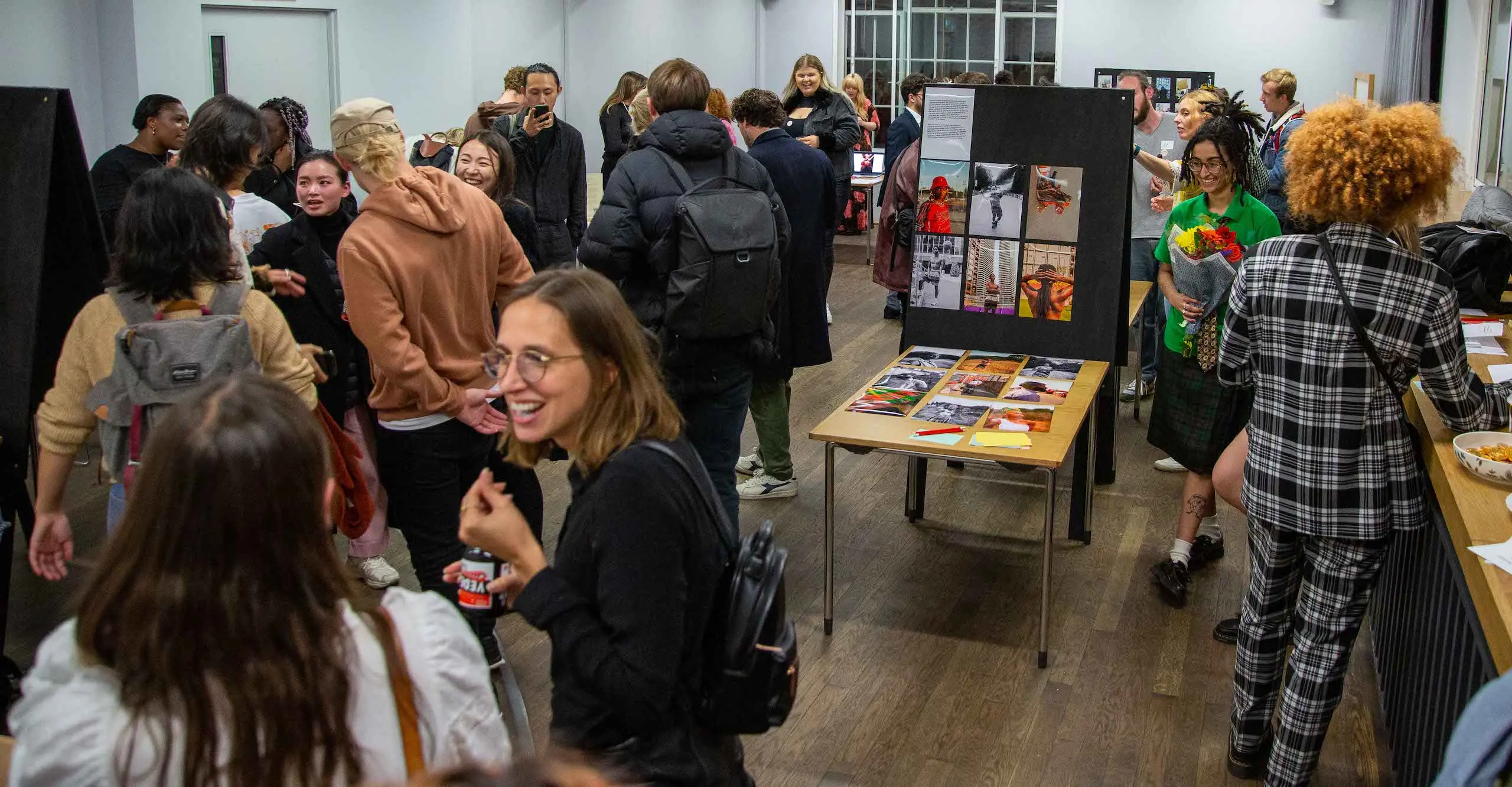 Colour photograph of people gathering and talking in a room 