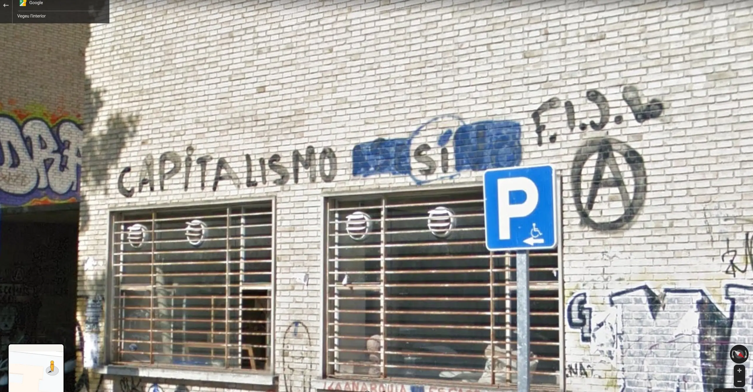 A screenshot of a the façade of a building on Google Street View with 'capitalismo si' graffitied 
