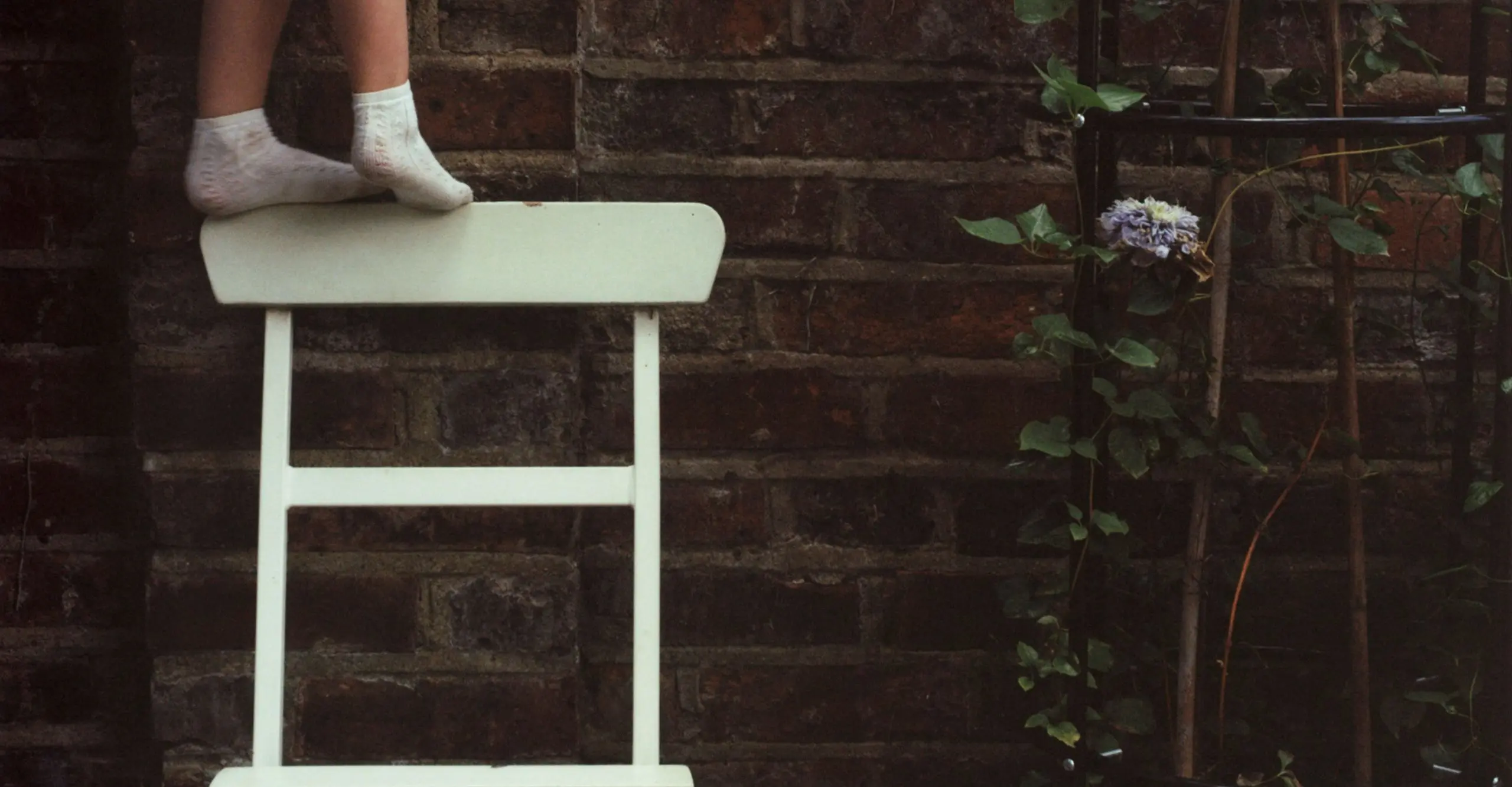 child's feet balancing on a garden chair