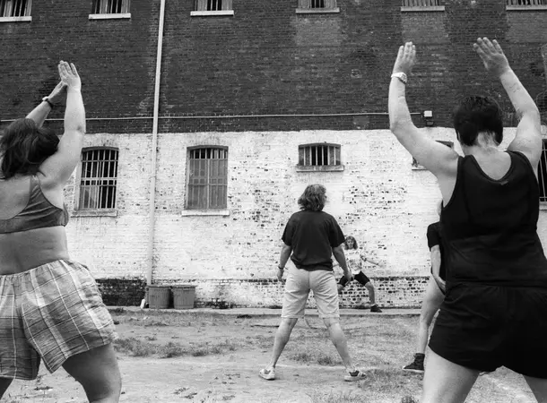 Black and white photograph of prisoners stretching in a prison-yard.
