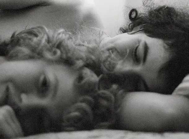 Black and white close-up photograph of two people who appear to be naked lying in bed.