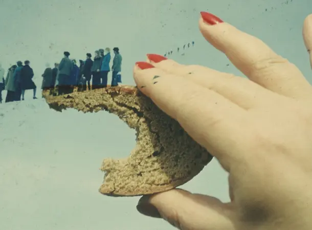 A vintage double exposed image of a hand with painted red nails, holding a crust of bread. An overlay of a group of people in winter coats are seemingly walking down the top of the crust of the bread.