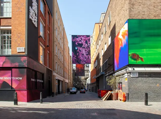 Image of The Photographers Gallery and Soho photography corner, an outdoor display mad eup of large banners on the opposite building to the gallery.
