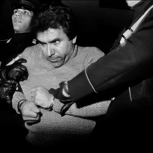 Black and white photograph of police officers holding a man in hand cuffs