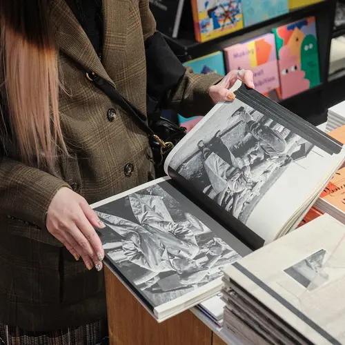A woman flicking through a photobook in a bookshop
