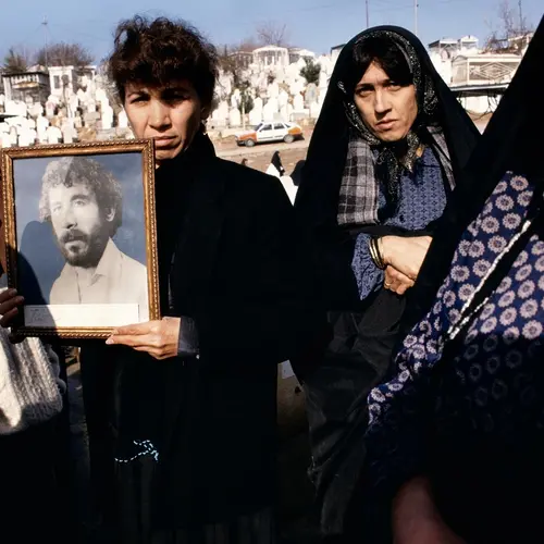 Susan Meiselas, Photographs of 20-year-old Kamaran Abdullah Saber are held by his family at Saiwan Hill cemetery. He was killed in July 1991 during a student demonstration against Saddam Hussein, Kurdistan, Northern Iraq, 1991 © Susan Meiselas/Magnum, all rights reserved
