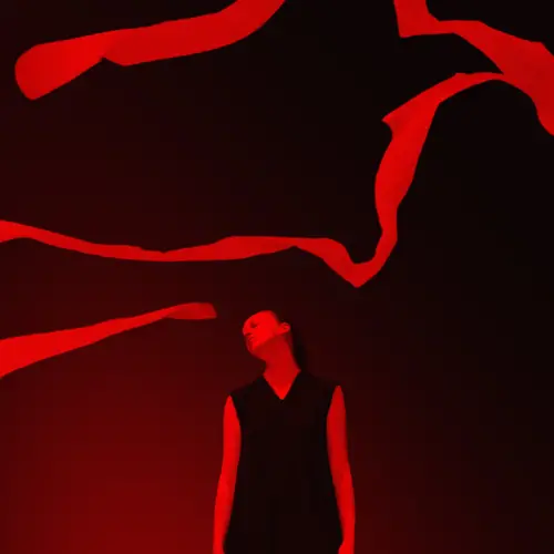 A dark and mysterious image a a woman stood with her head flopping to one side as if in a trance. Billowing fabric flies above her head. The image is two toned in black and deep red.