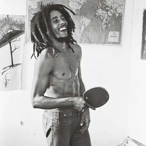 A candid shot of Bob Marley playing table tennis and smiling.