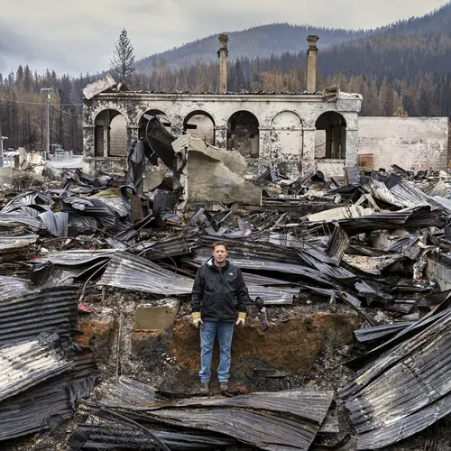 Photograph of a person in the middle of a burnt building