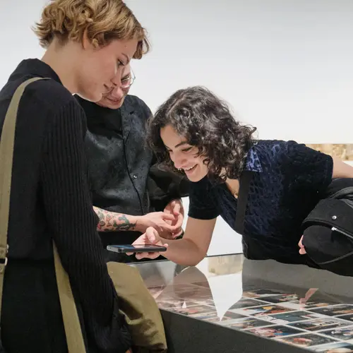 A small group of people bending to look closer at a display in a vitrine.