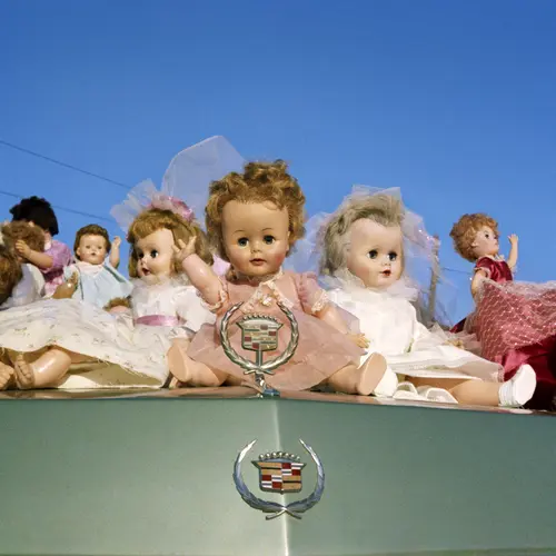 A collection of dolls on a car bonnet