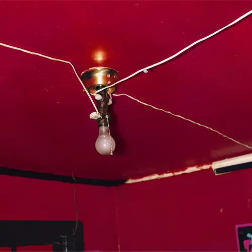 A lightbulb in the centre of a ceiling painted ruby red.