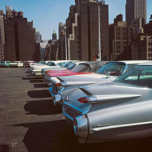 Row of 1950s style American cars parked with skyscrapers in background