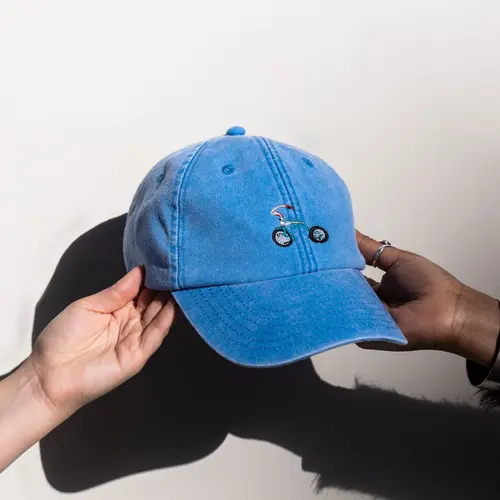 a blue cap with a stitched tricycle to the front