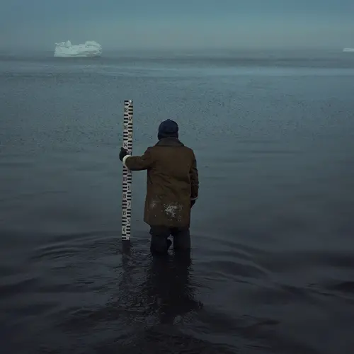 Man looking at iceberg standing in the sea