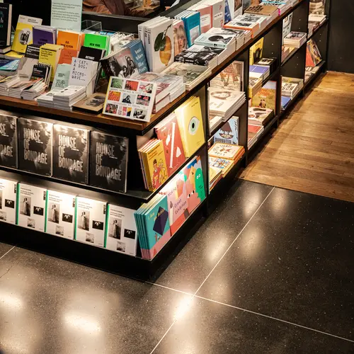 An image of the bookshop at The Photographers' Gallery. There is a shop clerk sat at a counter which is stocked with a selelction of books on sale.
