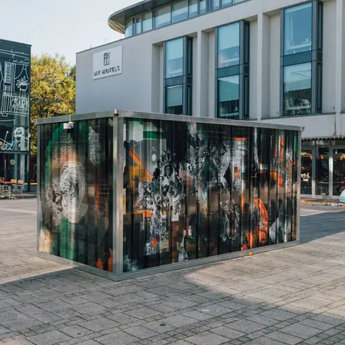 Install image from V1: Content Aware in which a large shipping crate installed with a camera is capturing images of itself in a mirrored window.