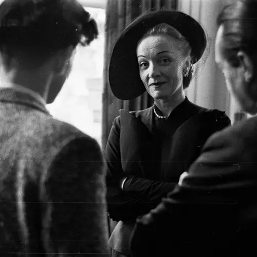 Black and white photograph of Marlene Dietrich standing in a small group of people